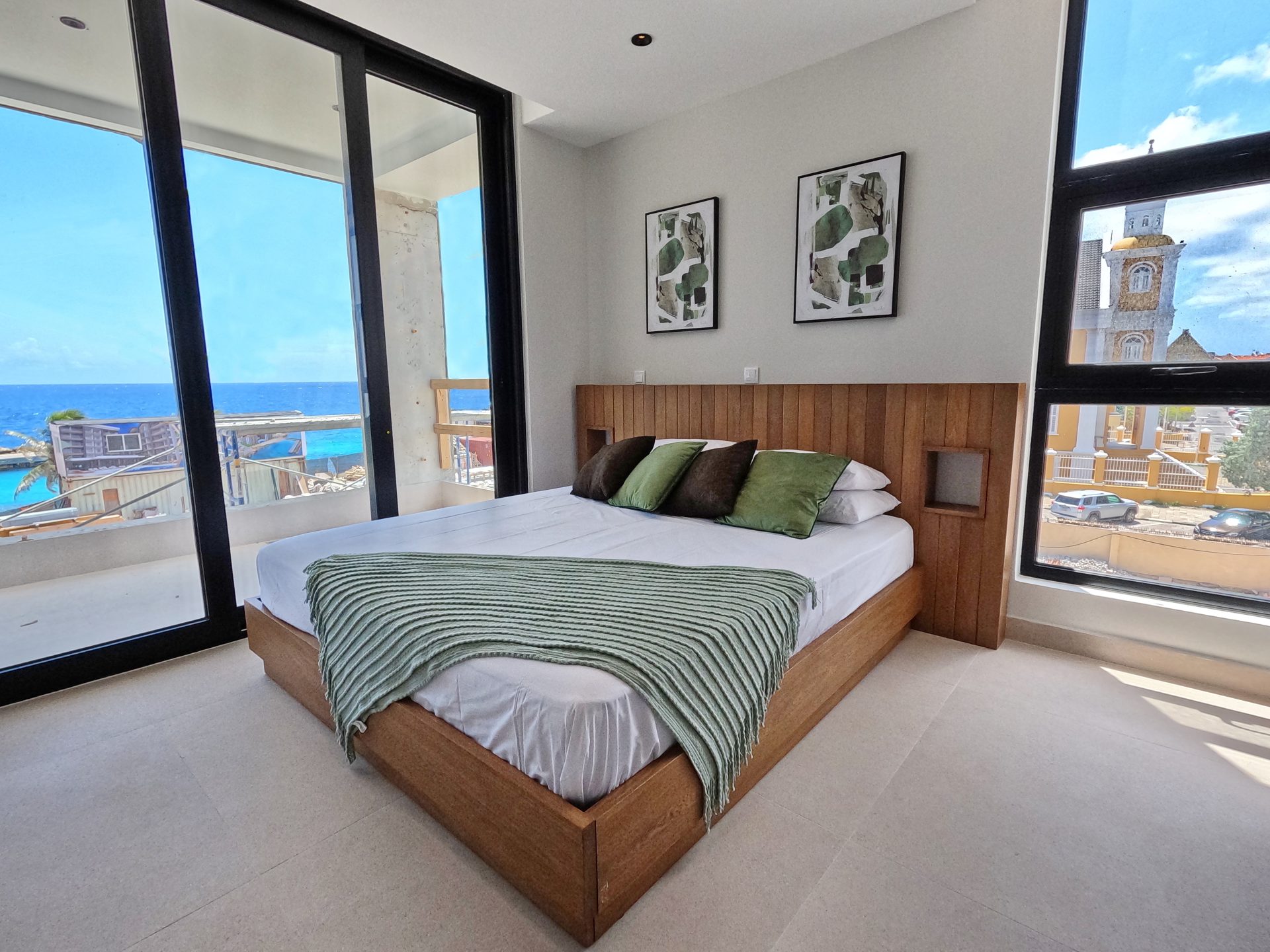 Moderne slaapkamer in Majestic Apartments & Hotel met uitzicht op zee en Punda, Curaçao, met bed en decoratieve kussens.