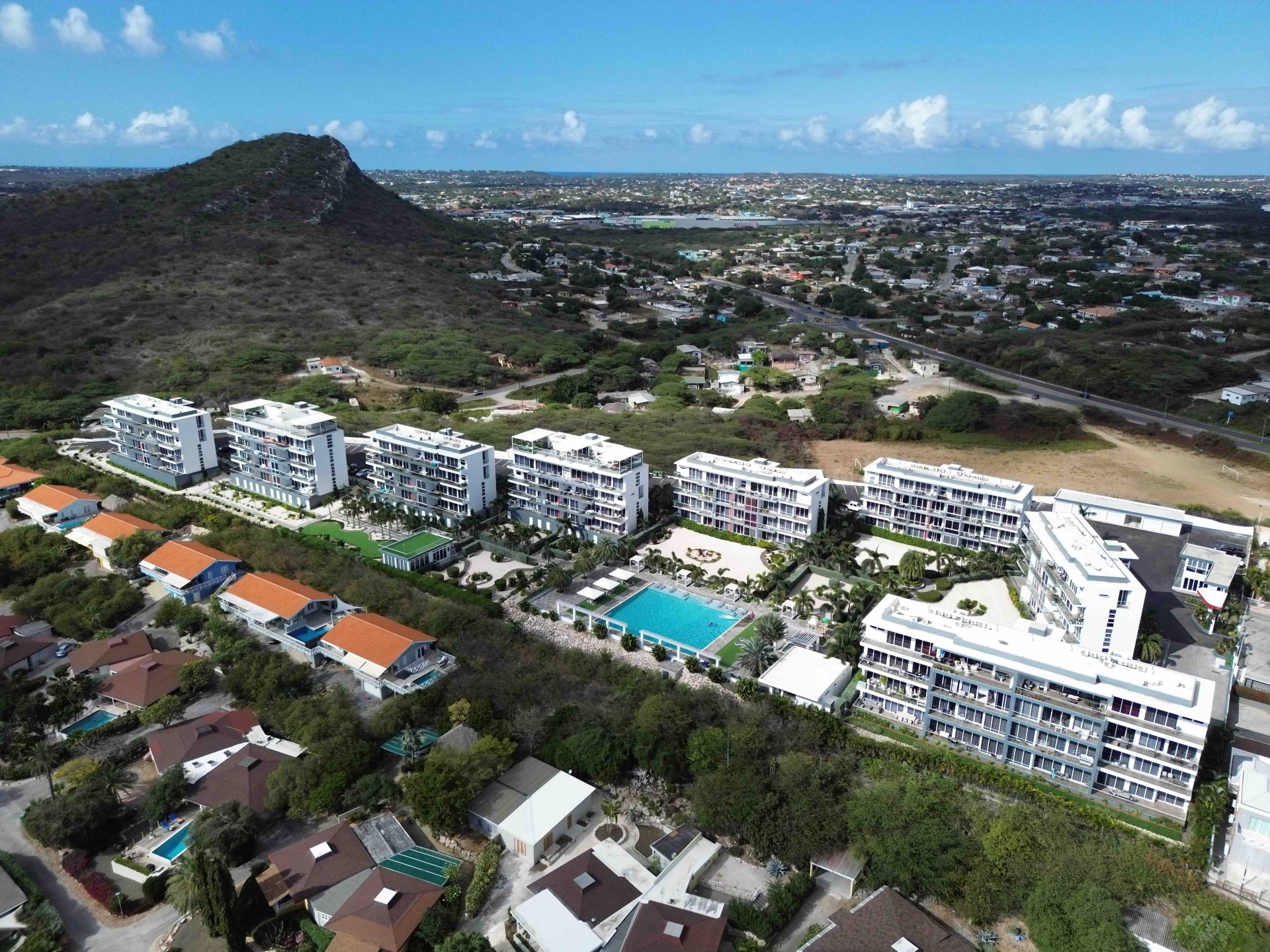 Aerial view of Grand View Residences featuring modern buildings, a swimming pool, and surrounding landscape in a residential area, highlighting rental properties and amenities.