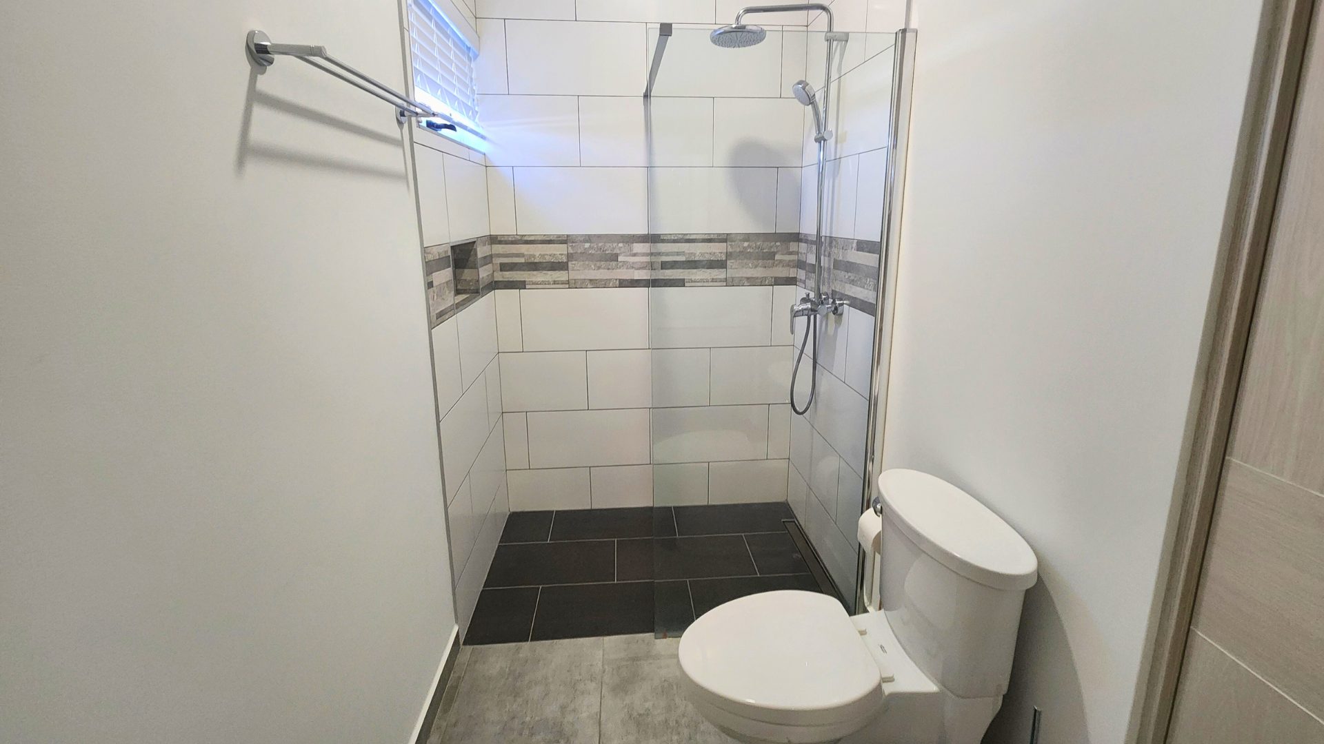 Modern bathroom featuring a glass shower enclosure, sleek tile design, and contemporary toilet, highlighting luxury finishes relevant to Grand View Residences H1 rental in Piscadera Baai.