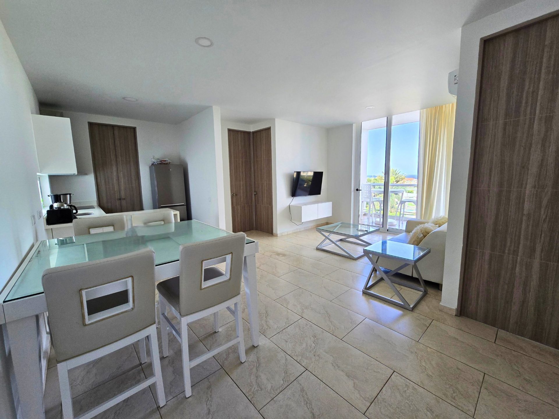 Moderne woonkamer in Grand View Residences B5 met glazen eettafel, comfortabele stoelen, en toegang tot balkon met uitzicht, ideaal voor lange termijn verhuur.