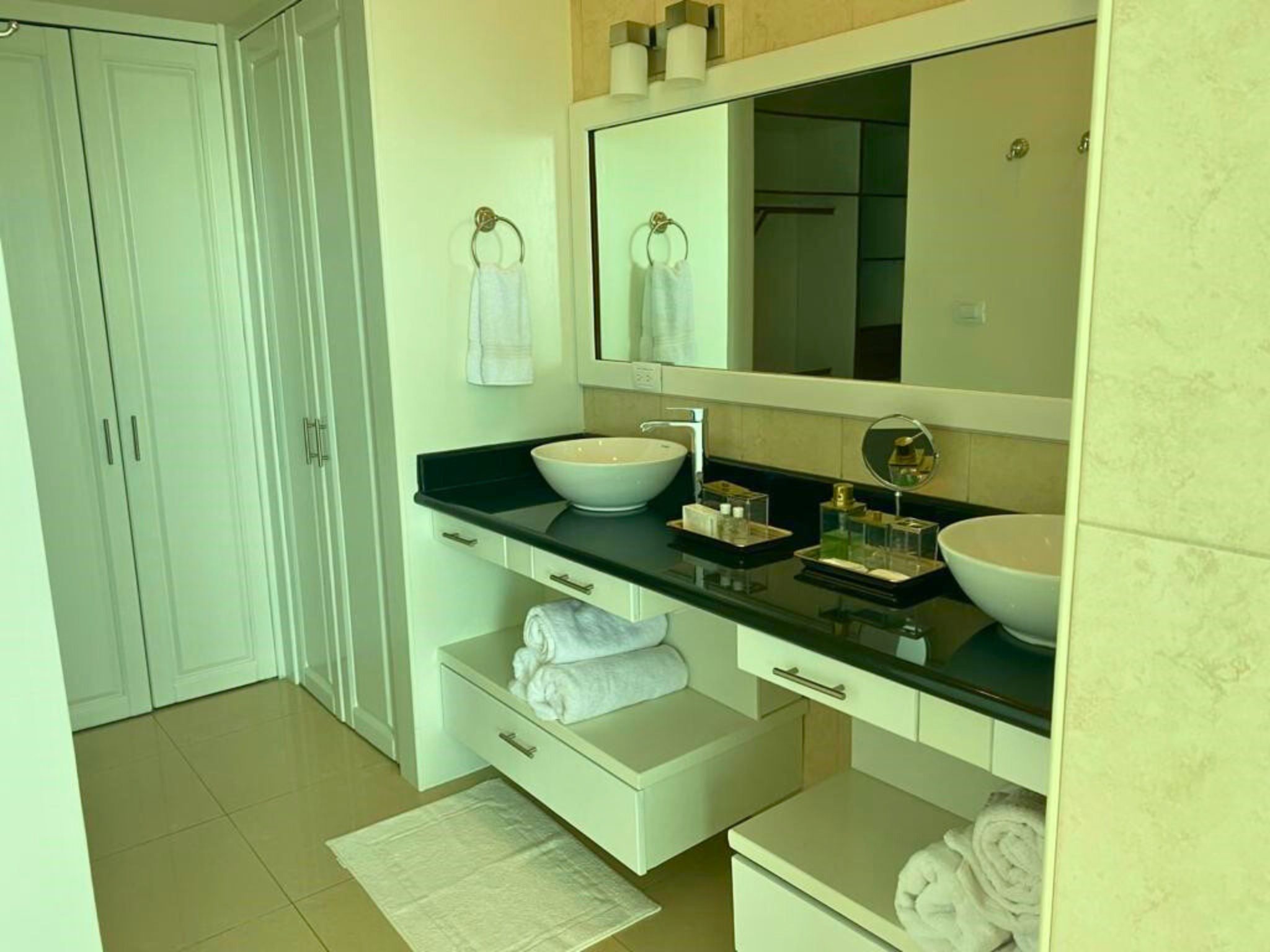 Luxe badkamer van de La Vista Resort Penthouse met moderne wastafels, opbergruimte, en handdoeken, benadrukt de hoogwaardige voorzieningen van het huurpand in Curaçao.