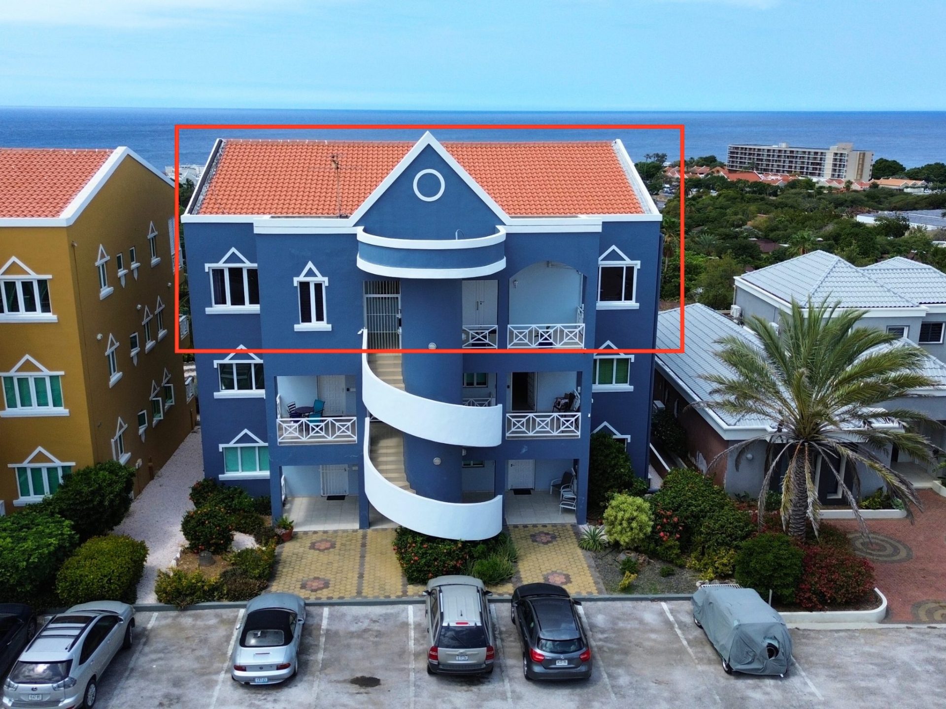 La Vista Resort Penthouse exterior view showcasing vibrant blue architecture, surrounded by lush greenery and ocean backdrop, emphasizing luxury rental property in Curaçao.