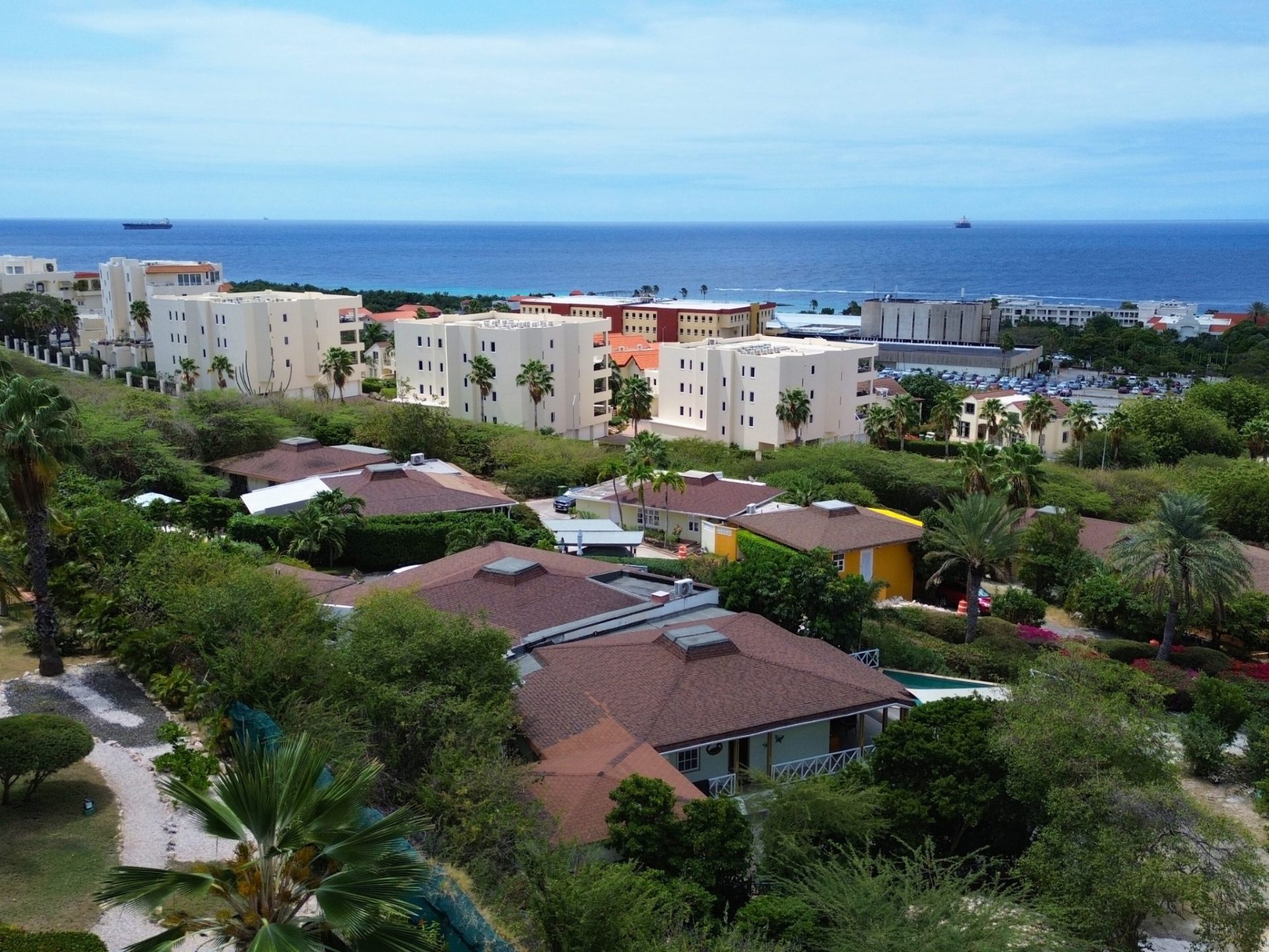 Aerial view of La Vista Resort showcasing luxury penthouses, lush greenery, and the Caribbean Sea in the background, highlighting the serene environment and upscale living in Curaçao.