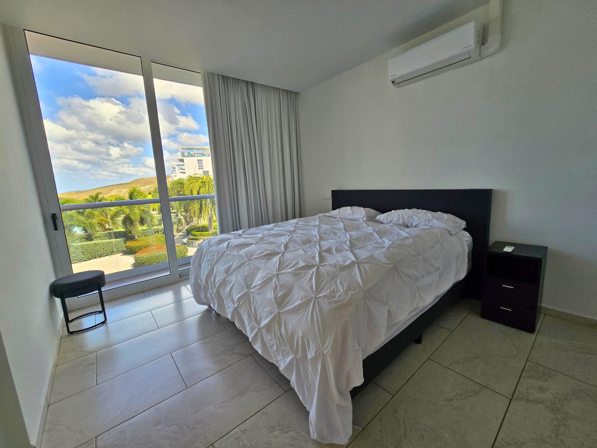 Slaapkamer in Grand View Residences B5 met uitzicht op tuin en zwembad, moderne inrichting, tweepersoonsbed en airconditioning.