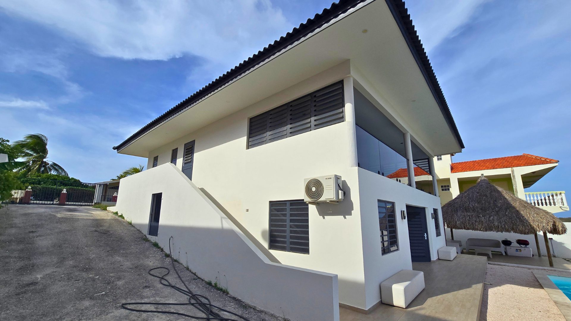 Moderne twee-verdiepingen woning in Sunset Heights, Curaçao, met luchtbehandelingsunit, toegangstrap en uitzicht op het zwembad.