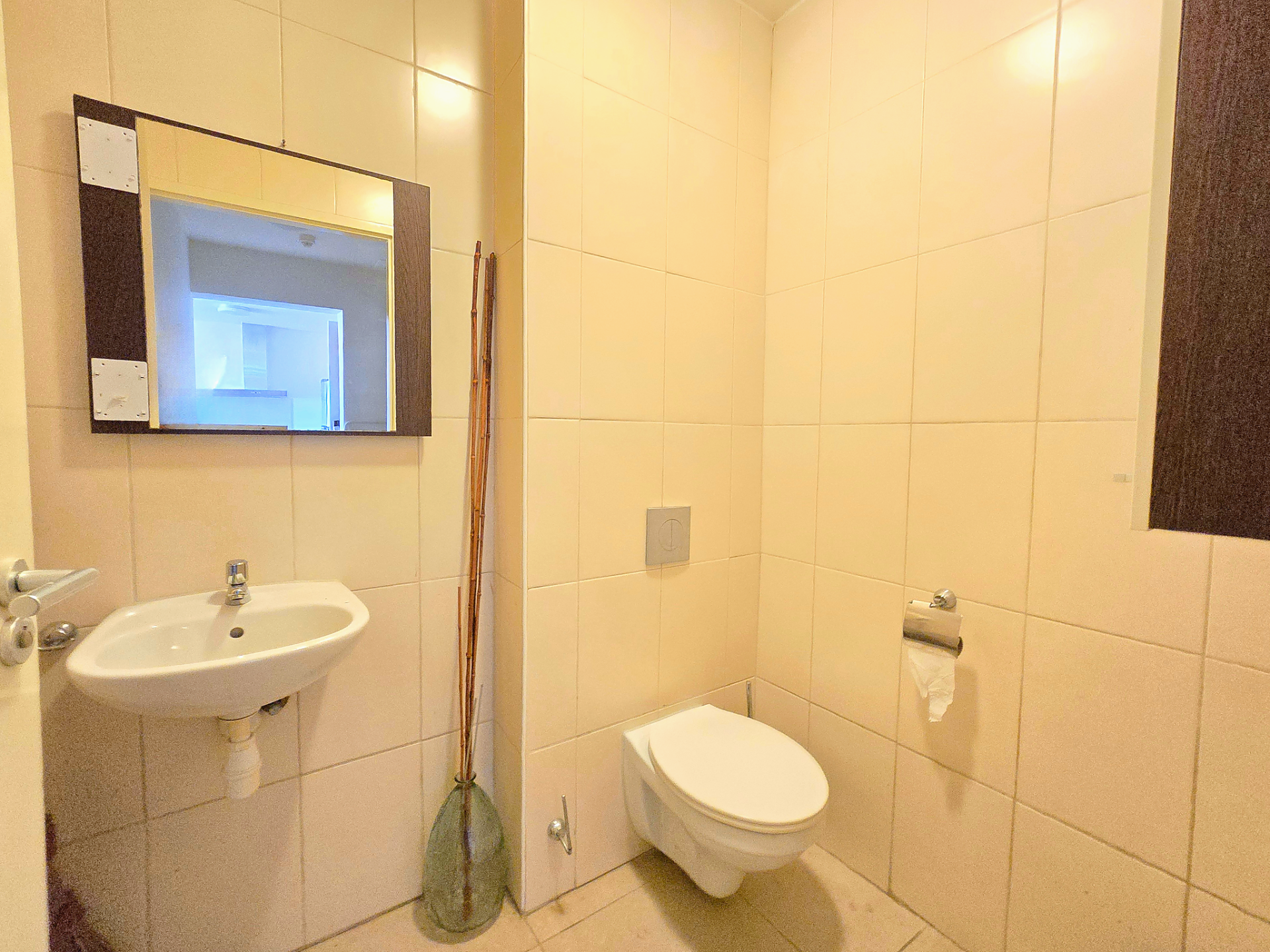 For rent Blue Bay 1-bedroom apartment - bathroom with toilet, shower, sink, and beige wall tiles.