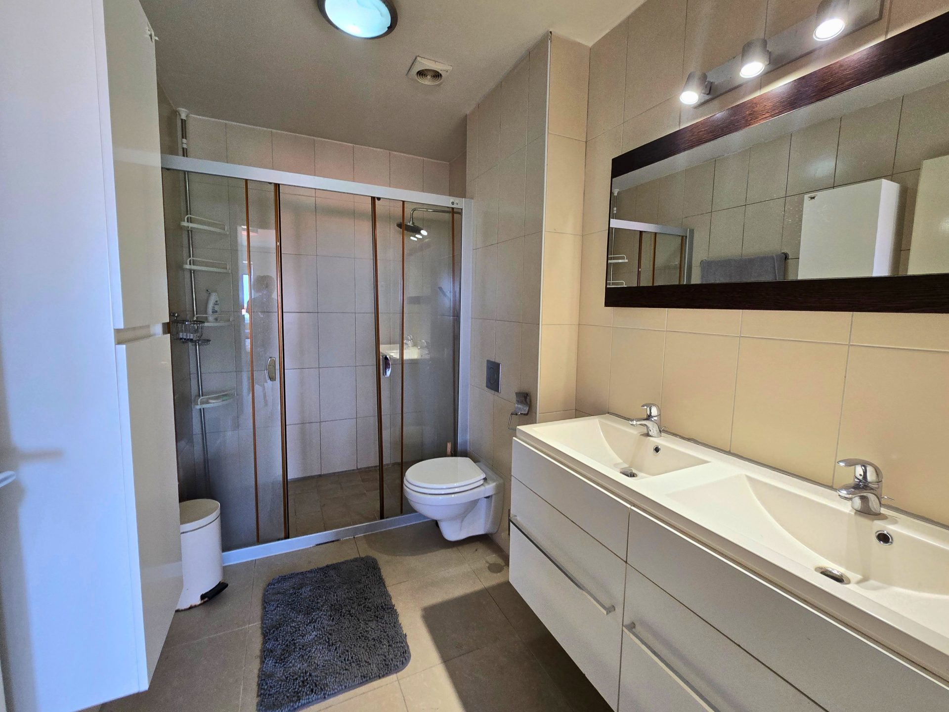 For rent Blue Bay 1-bedroom apartment - bathroom with glass shower, vanity, and light tile finishes.