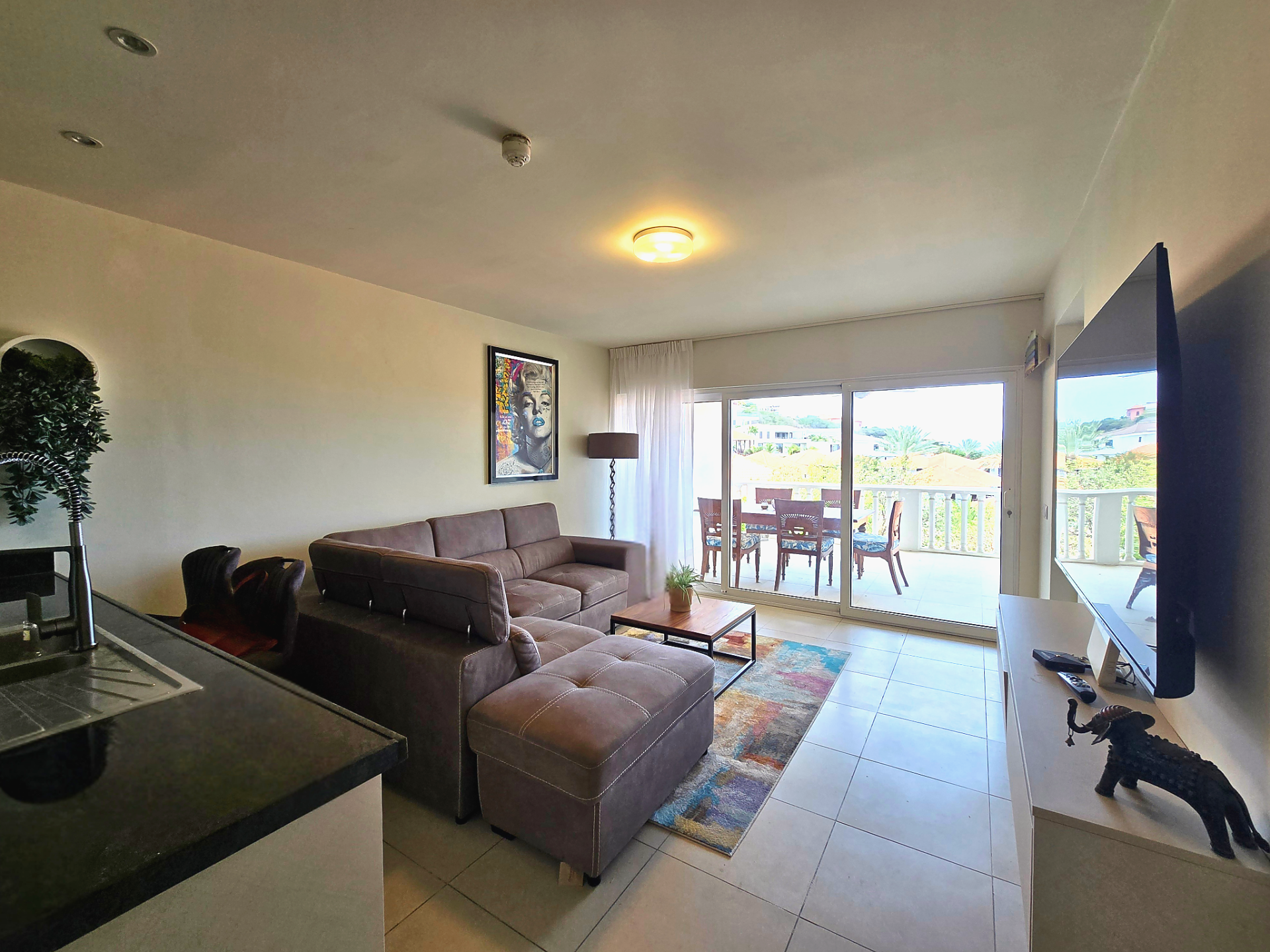 For rent Blue Bay 1-bedroom apartment - furnished living room with sofa, TV, and balcony access.