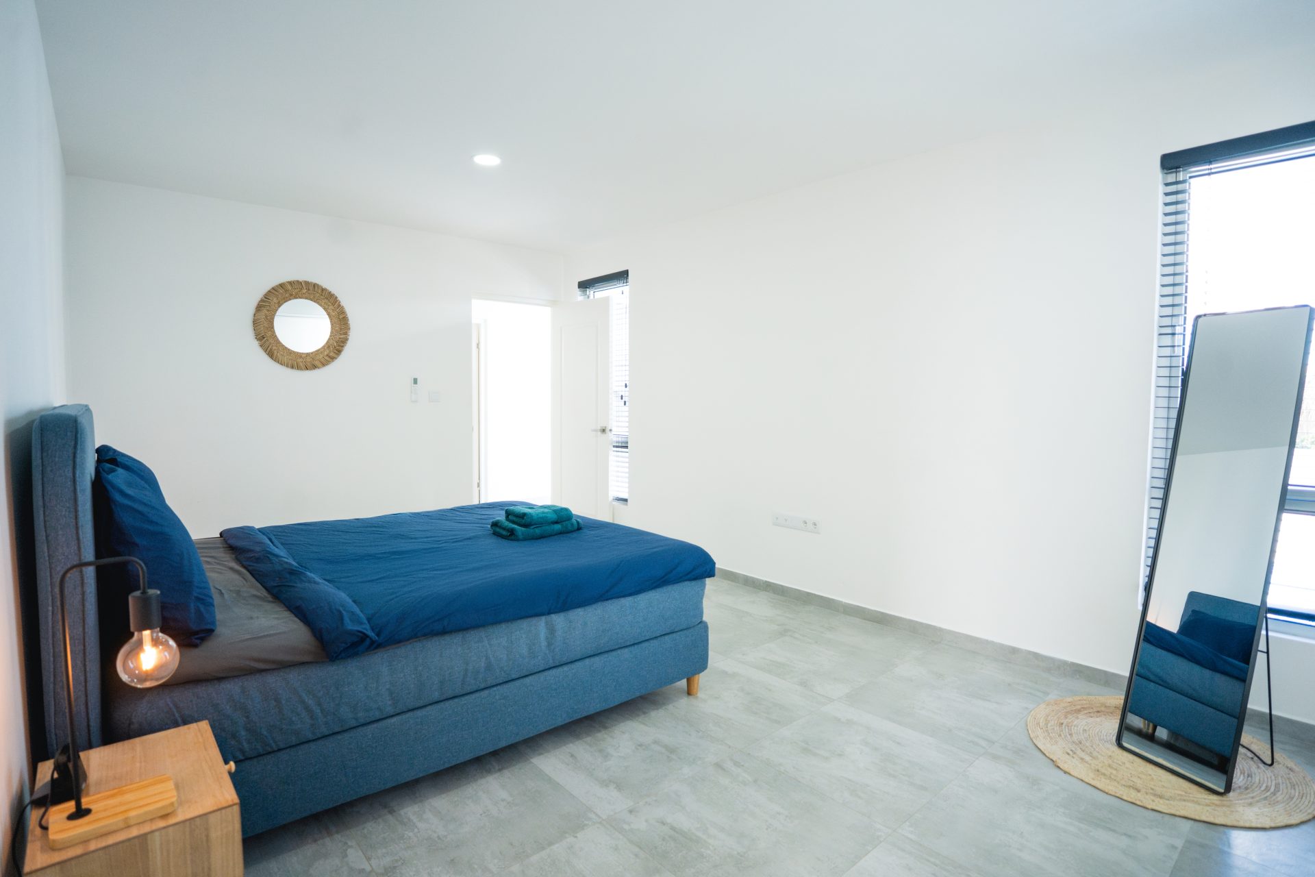 Curacao real estate for sale – Master bedroom featuring a king-size bed, minimalist decor, and natural light.