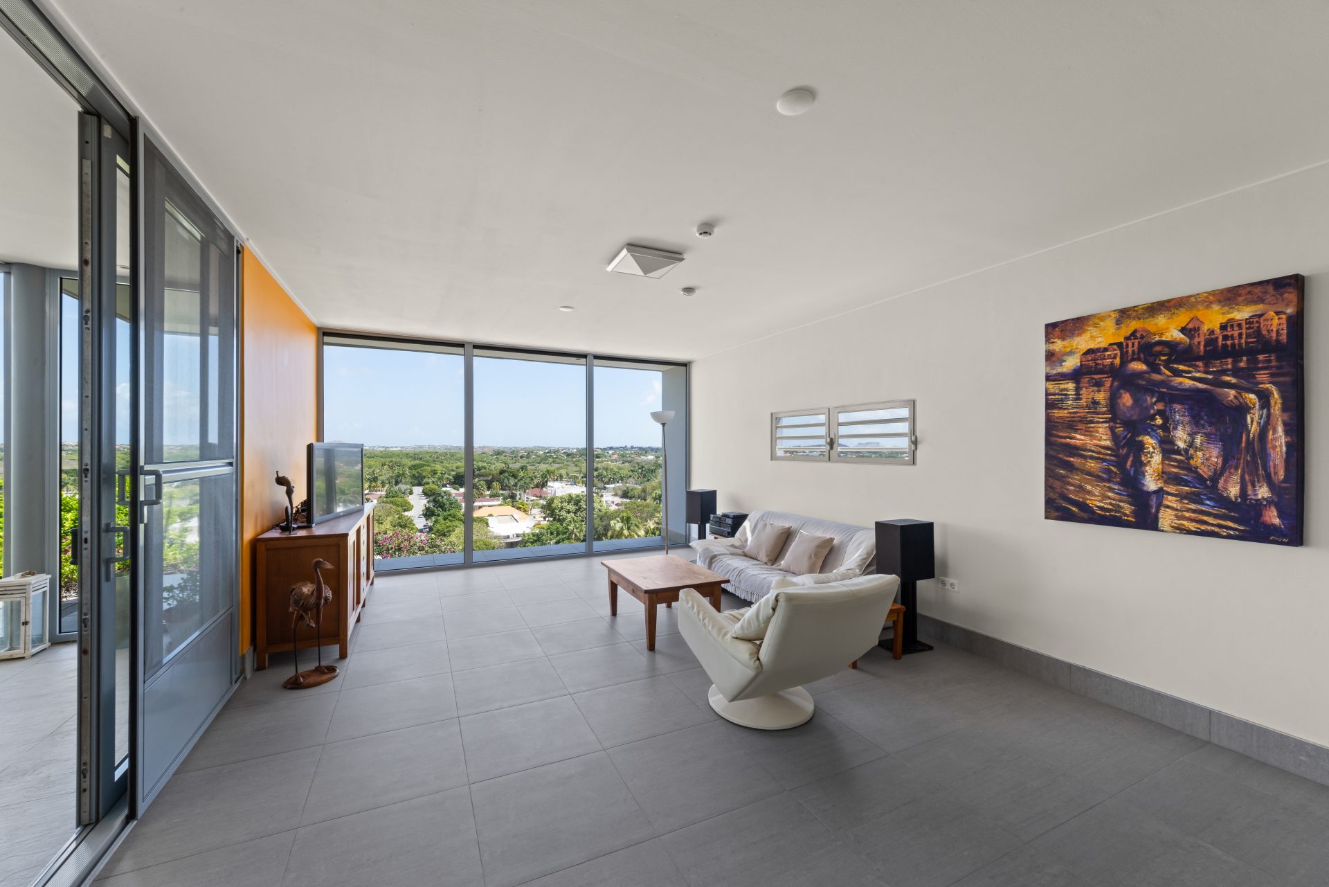 Curaçao real estate for sale bright open-plan living room with large windows and modern furnishings.