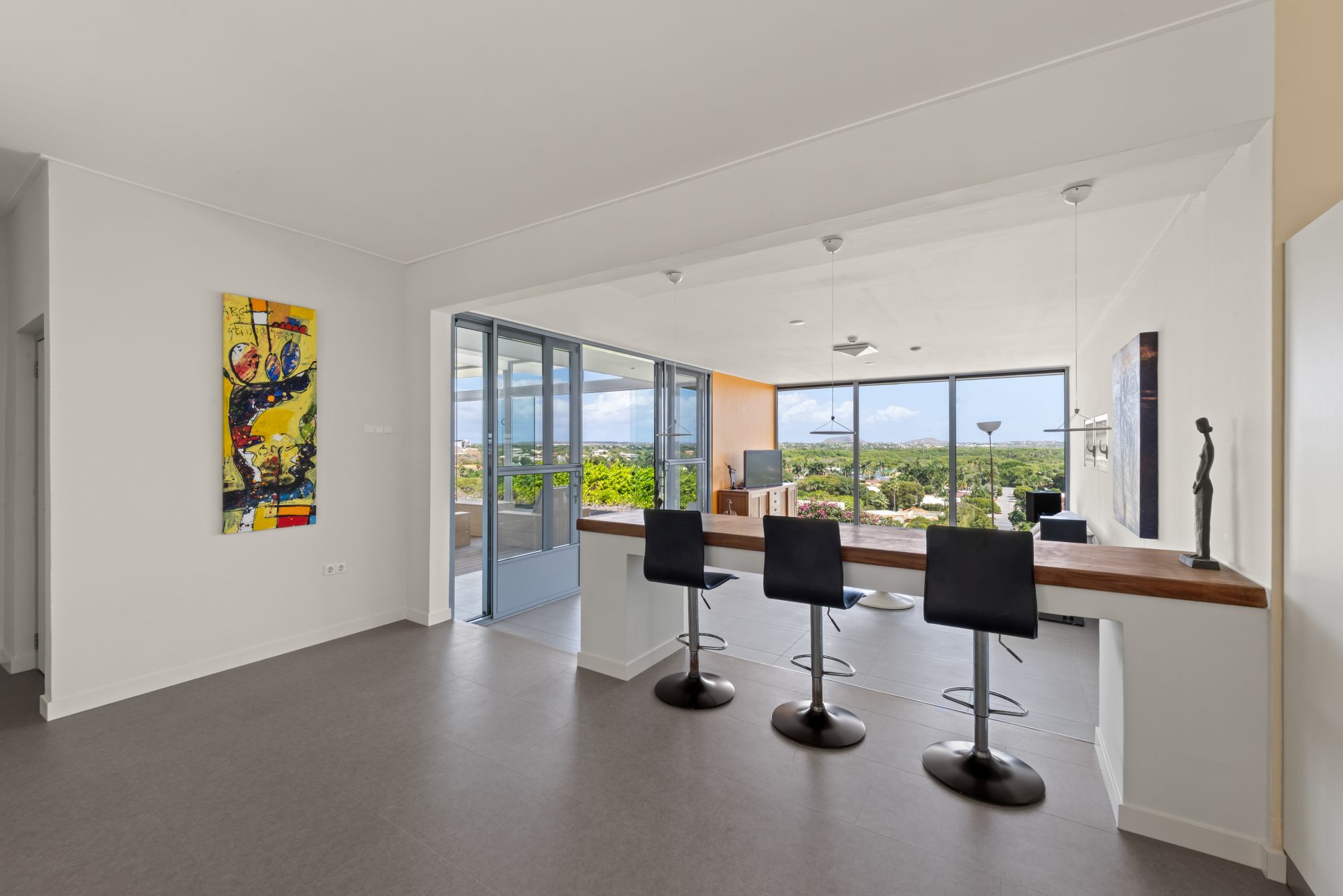 Curaçao real estate for sale minimalist interior space with bar stools and open kitchen layout.