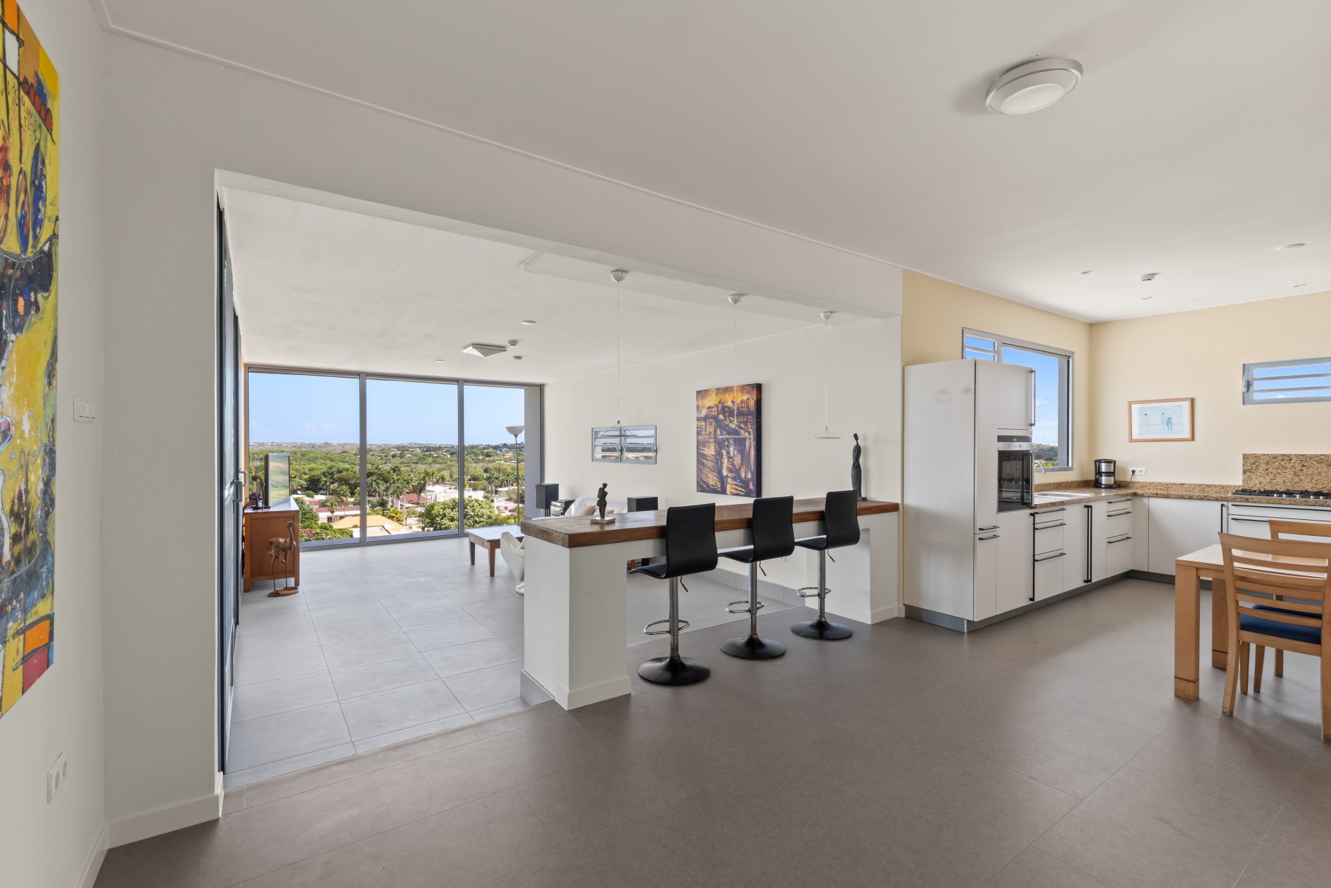 Curaçao real estate for sale minimalist interior space with bar stools and open kitchen layout.