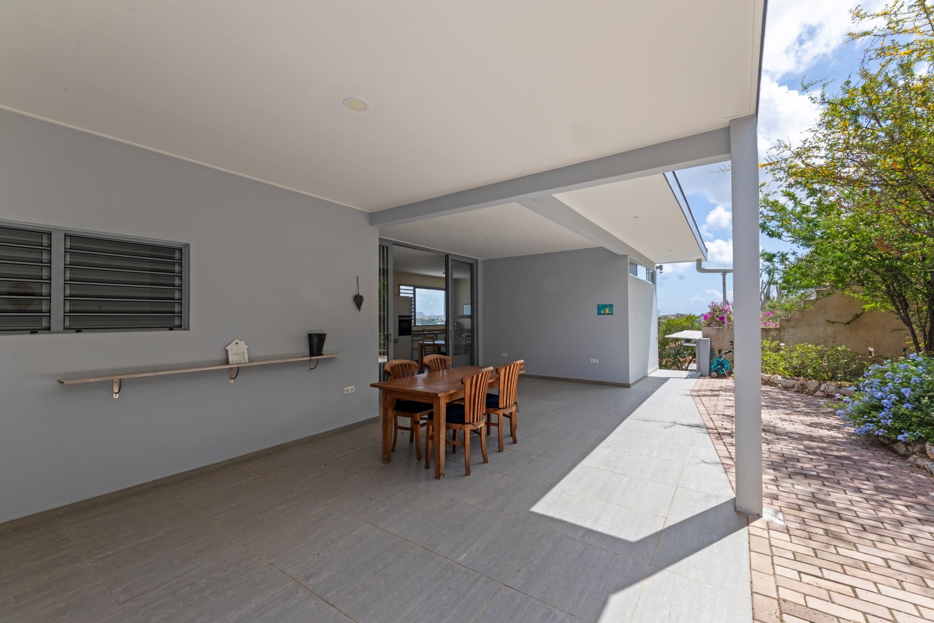 Curaçao real estate for sale covered outdoor dining area with wooden table and garden surroundings.