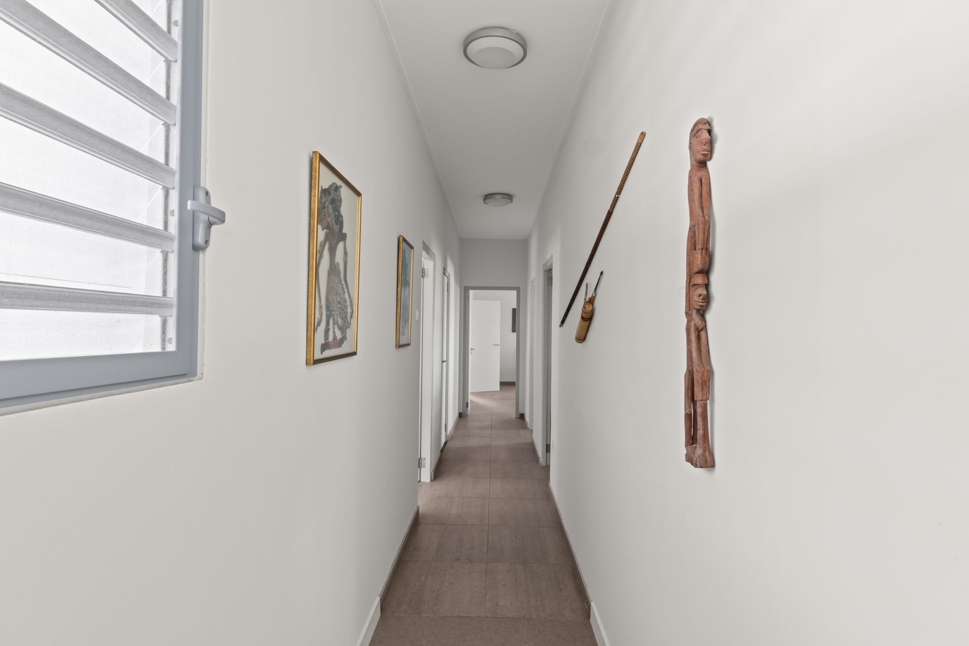 Curaçao real estate for sale expansive wooden deck corridor alongside infinity pool and glass façade.