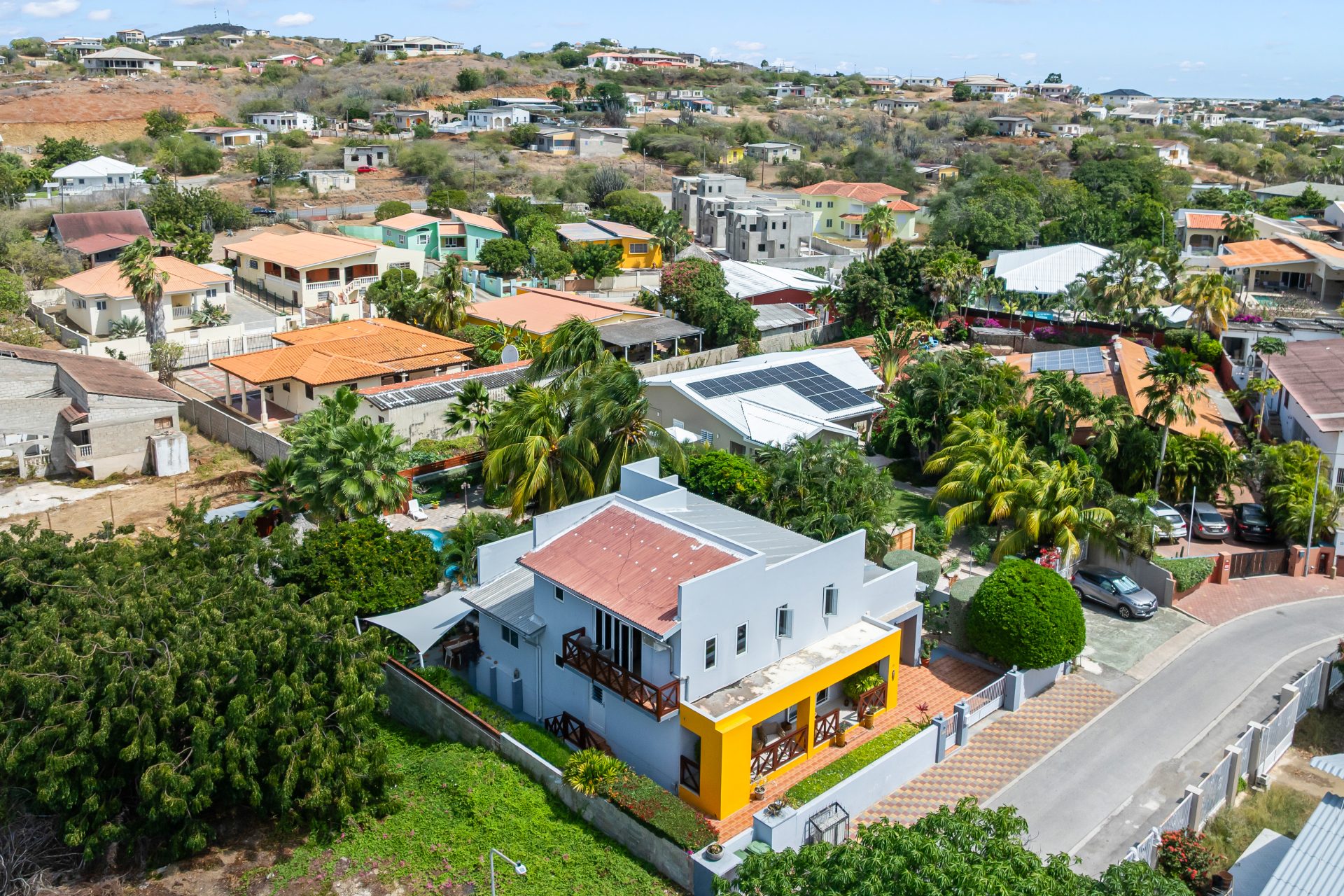 jan thiel villa for sale - elevated aerial view of modern yellow-accented villa in residential Jan Thiel area