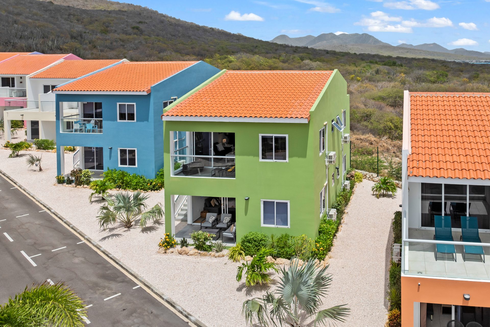 punta azul ocean resort unit for sale - exterior view of green two-story apartment building with balconies and tropical landscaping